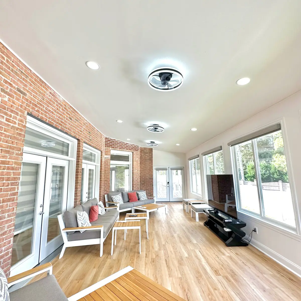 Long sunroom addition with brick wall, recessed lighting and LVP flooring
