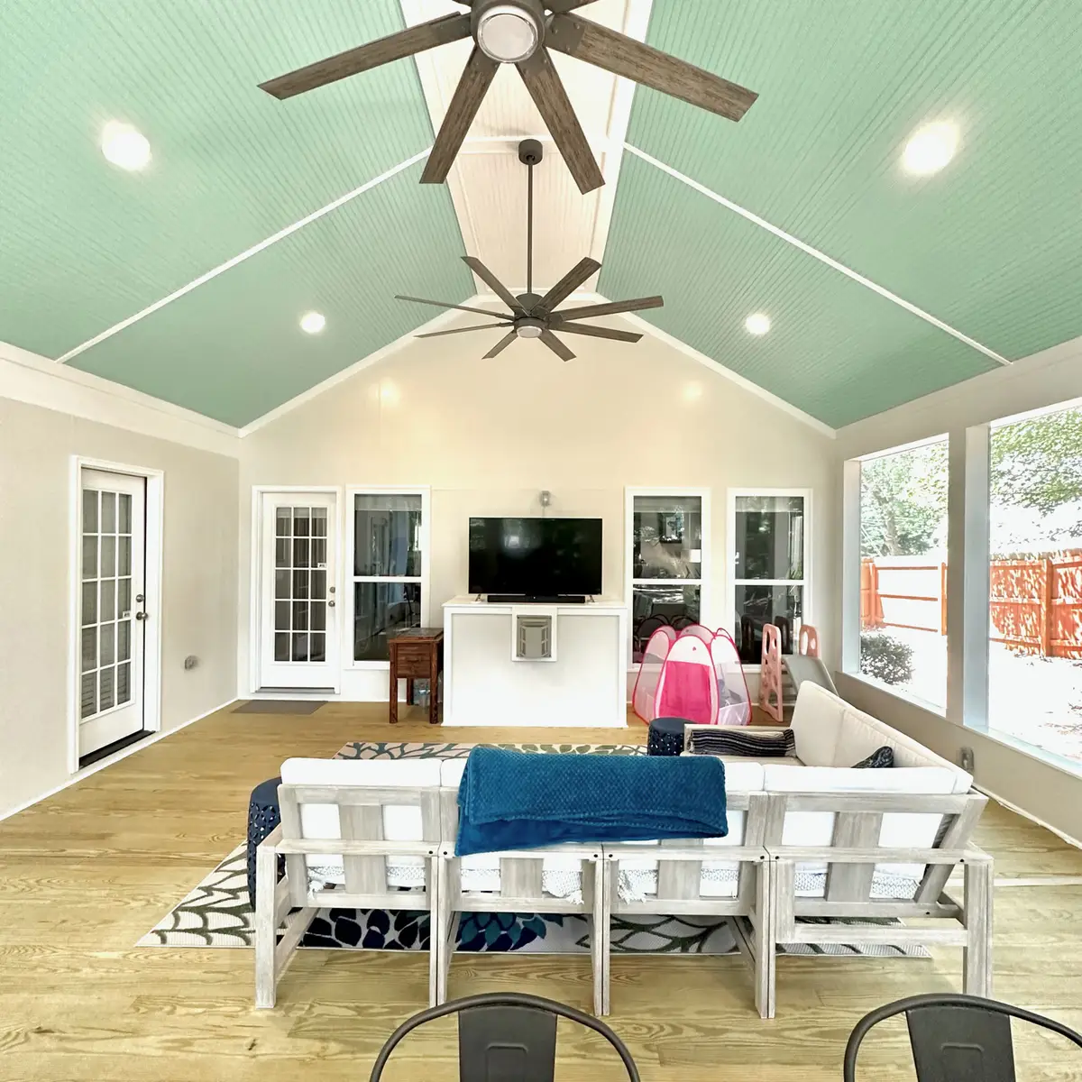 Screened porch living area with gabled ceiling and TV