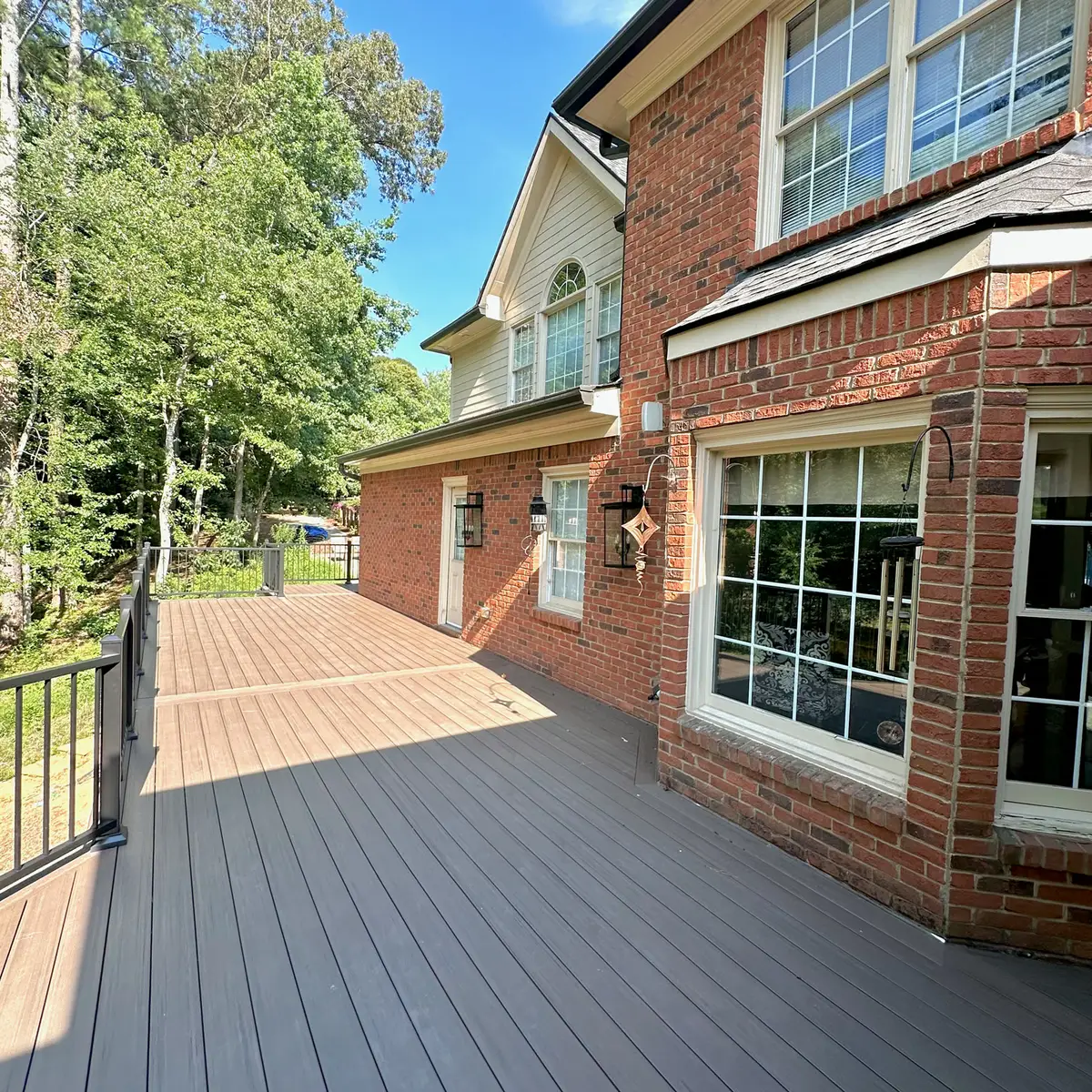 Composite deck wrapping a brick home with black railings