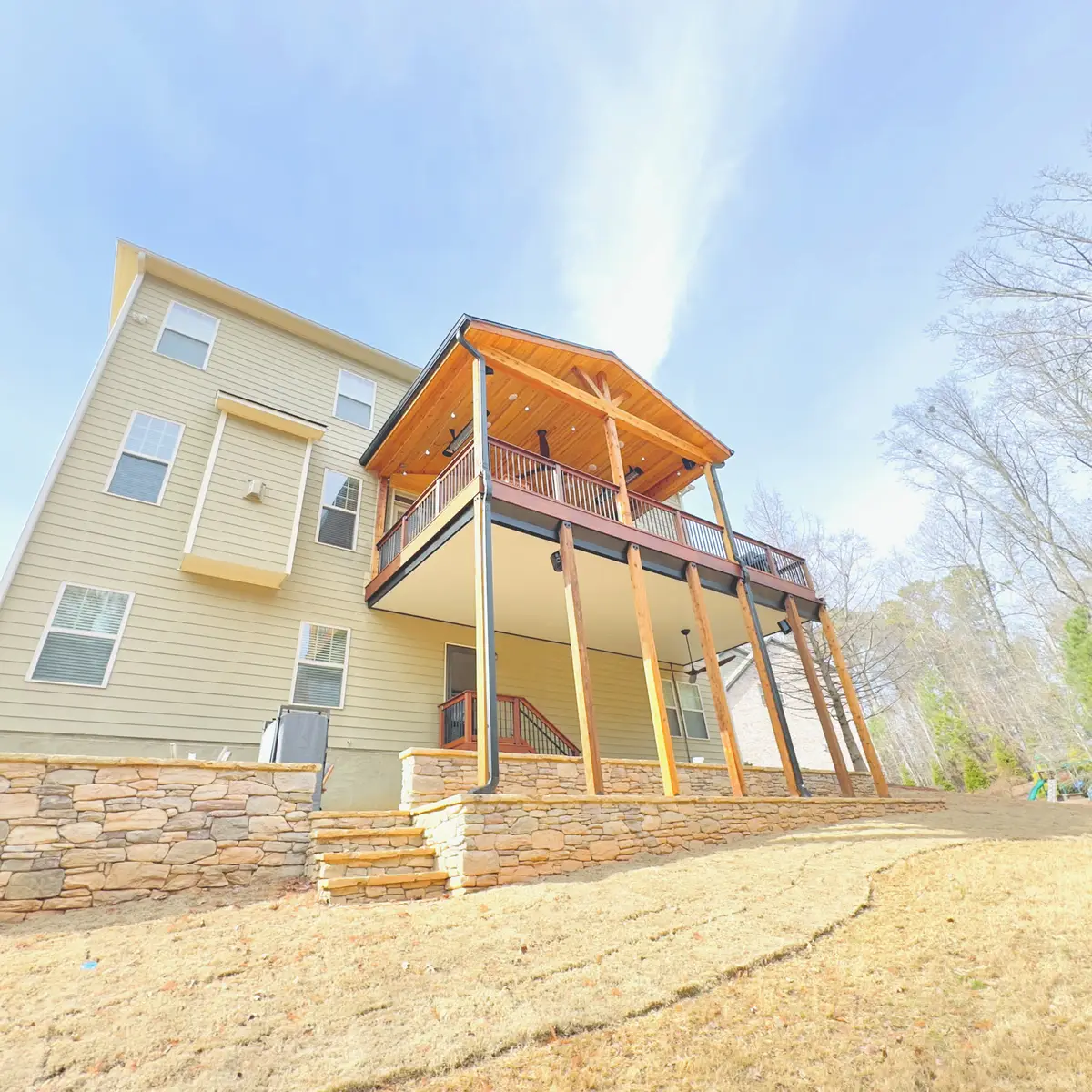 Two-level covered deck with cedar roof on a tan home