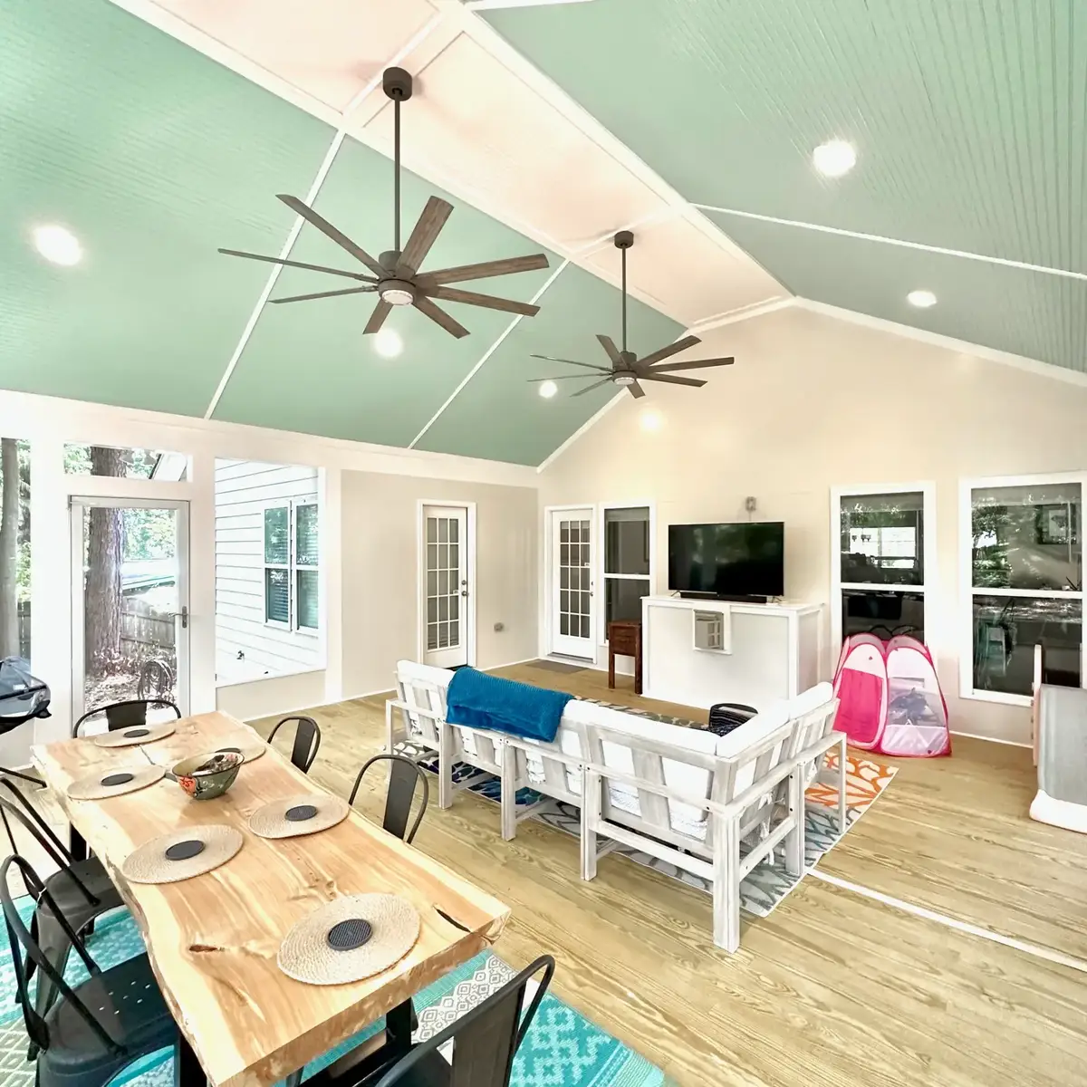 Dining area of the Atlanta screen room with live-edge table beneath the gabled bead-board ceiling