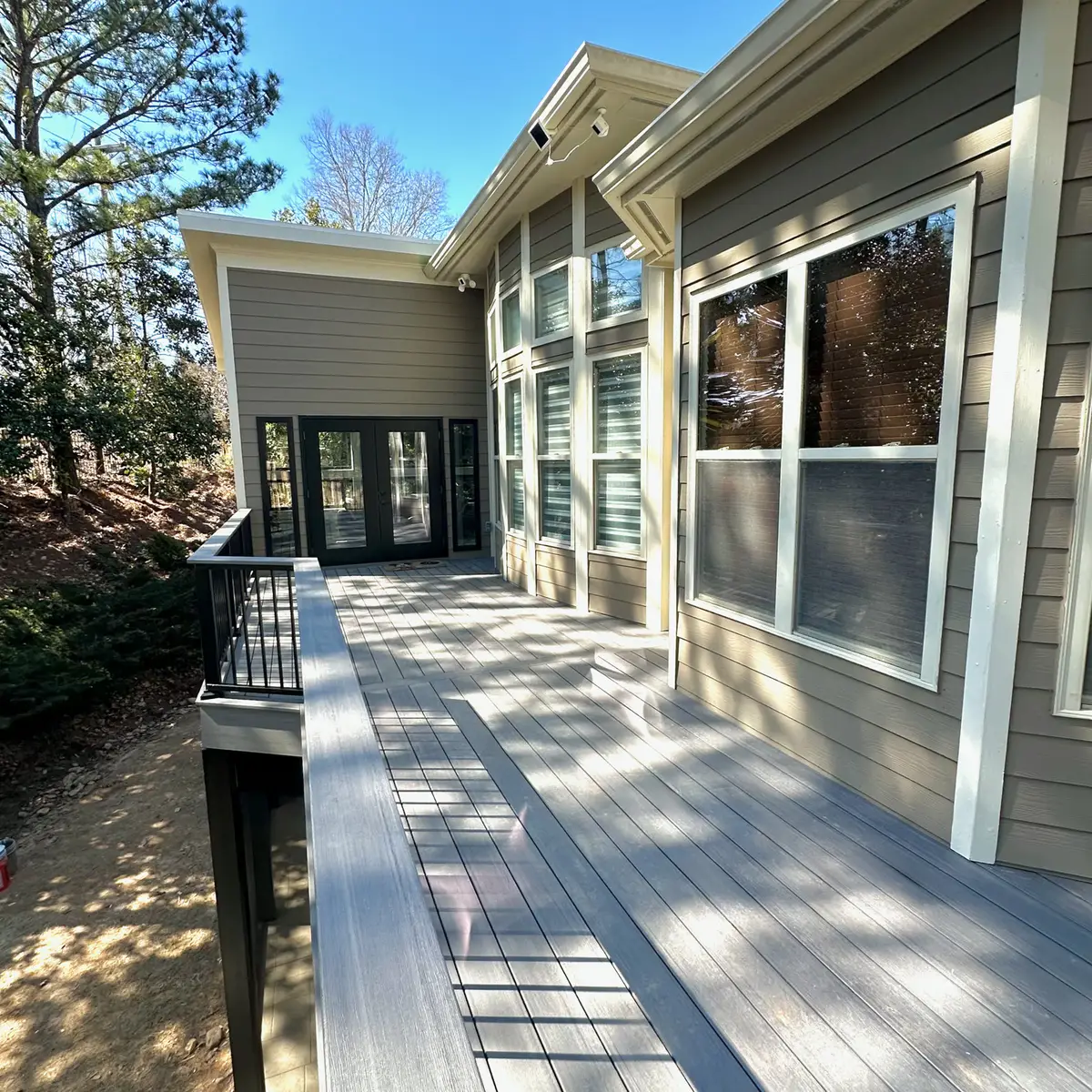 Composite deck along a grey home with black railings