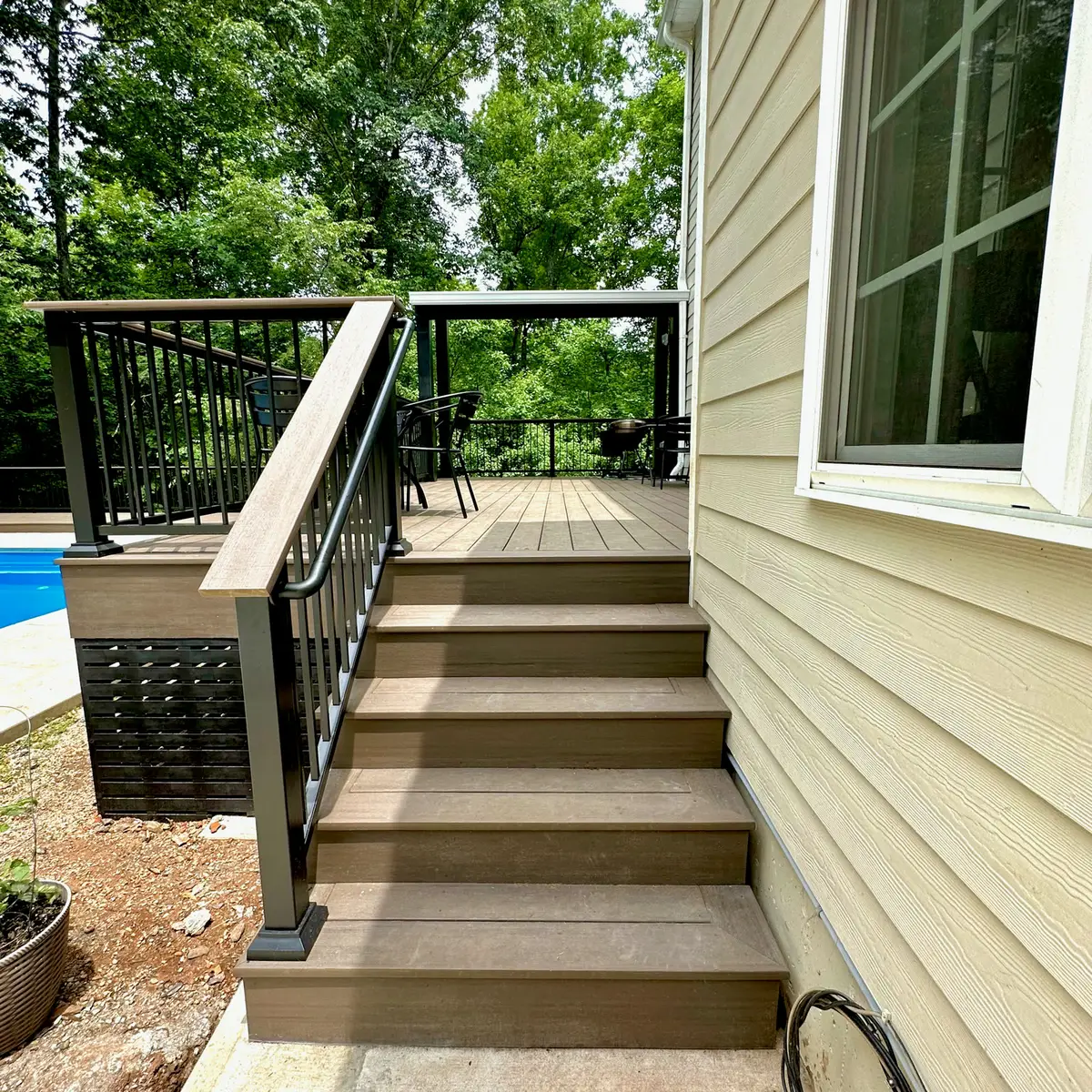 Composite deck stairs with black aluminum railings to a pool