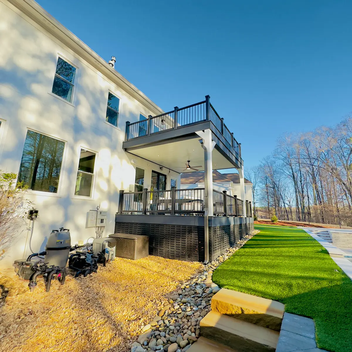 Two-level deck with black railings beside turf lawn