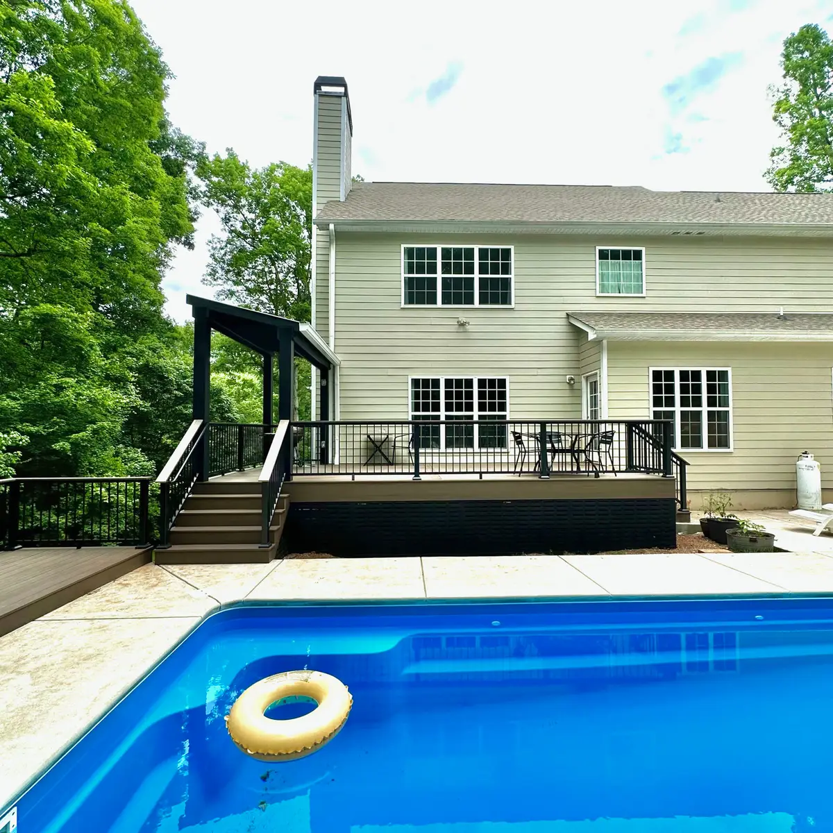 Low-maintenance pool deck with pergola on a two-story home
