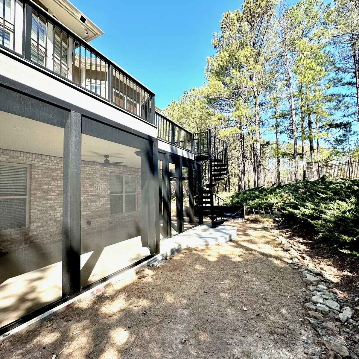 Screened patio under an upper deck with spiral stairs