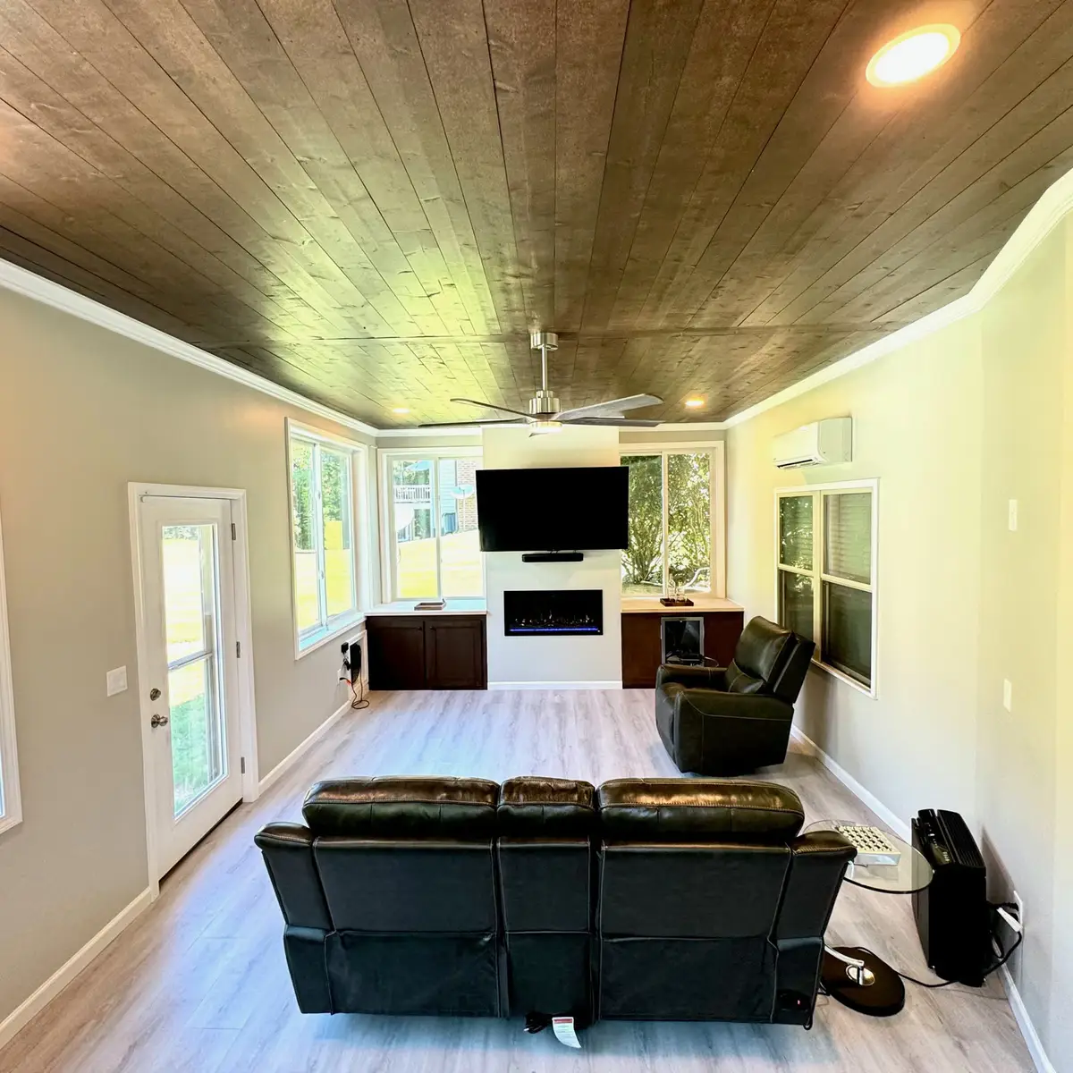 Sunroom with dark wood ceiling, TV and recliners