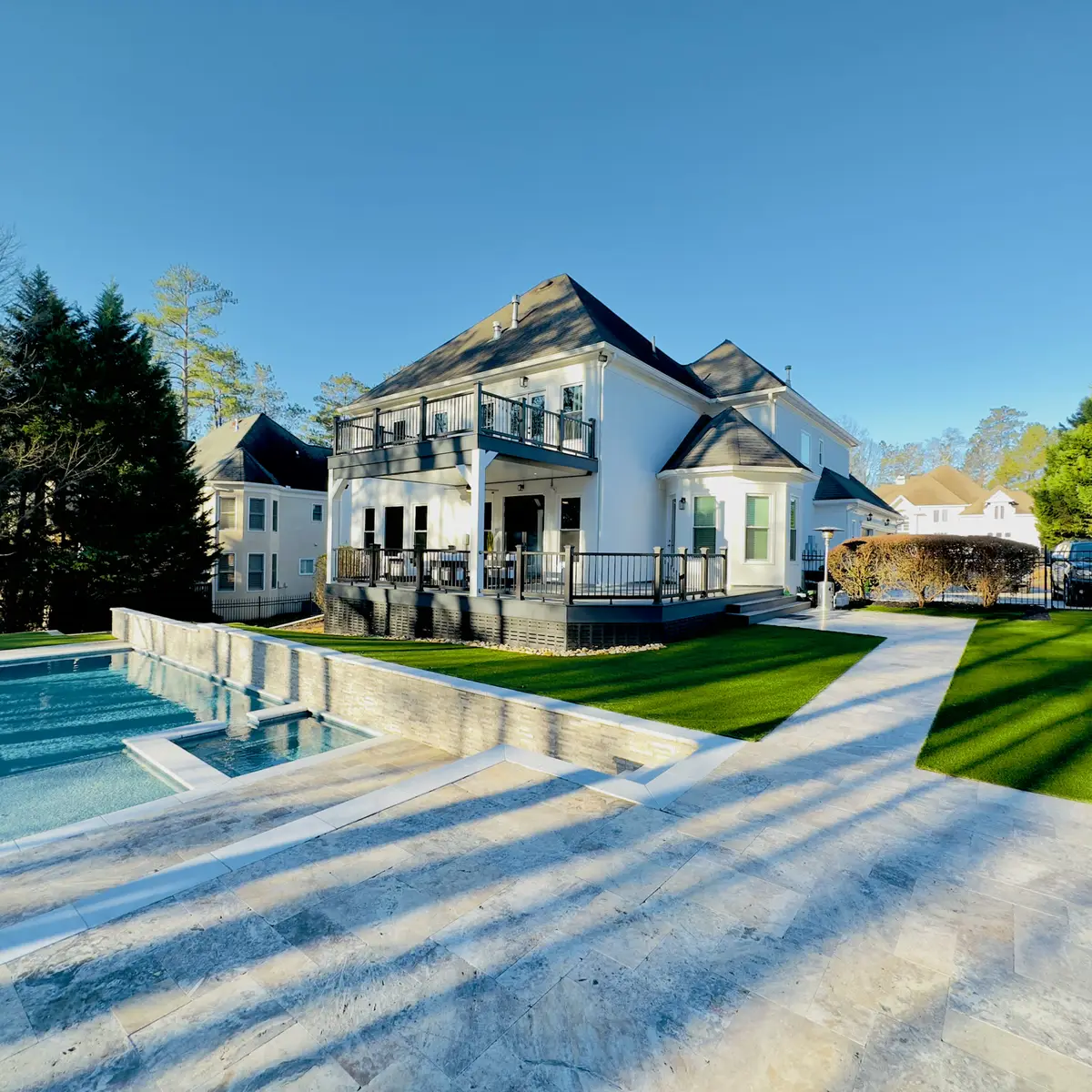 Two-story deck on a white home overlooking a pool