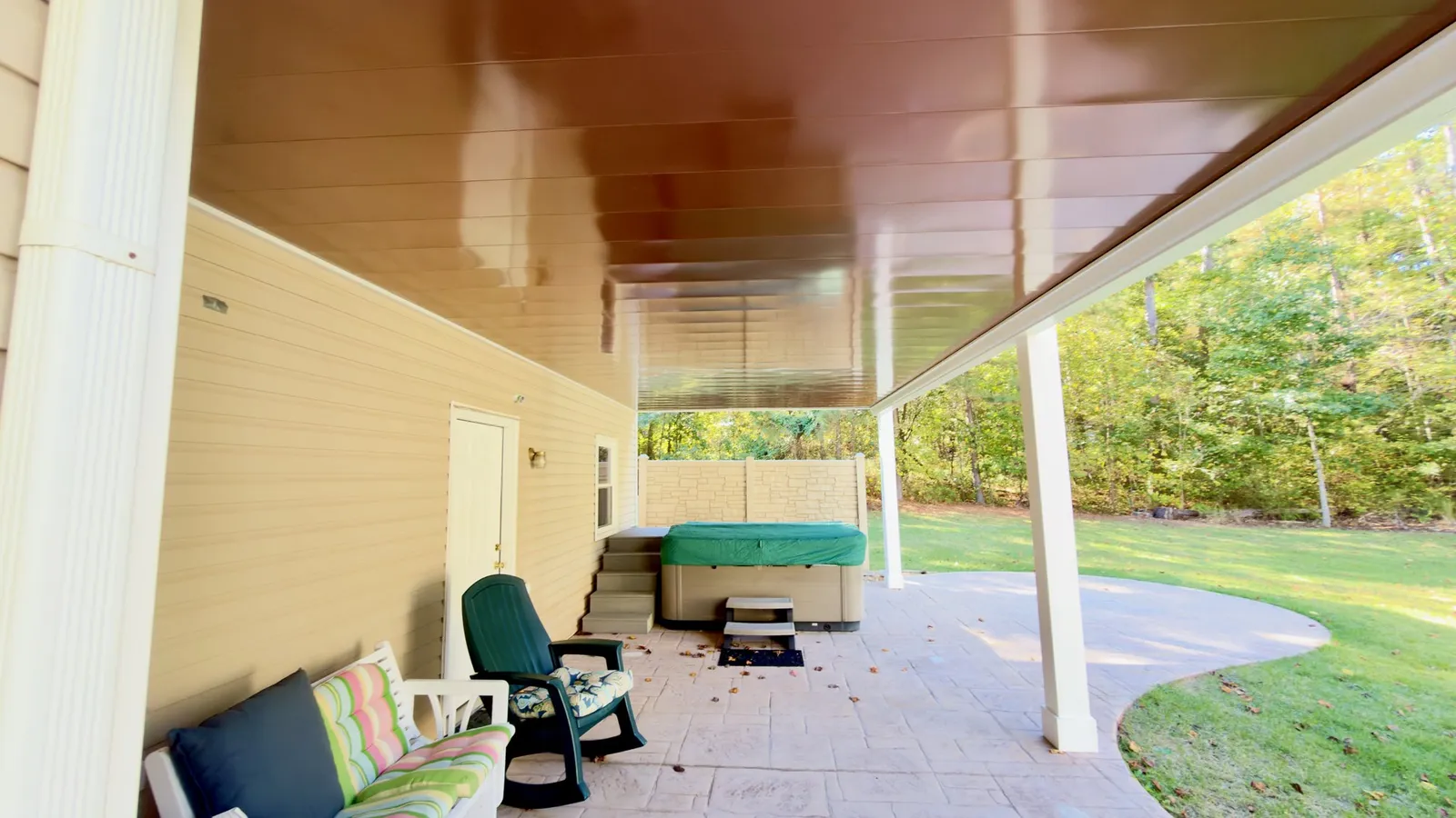 Looking out from the dry space under the deck, past the white PVC-wrapped posts to the yard