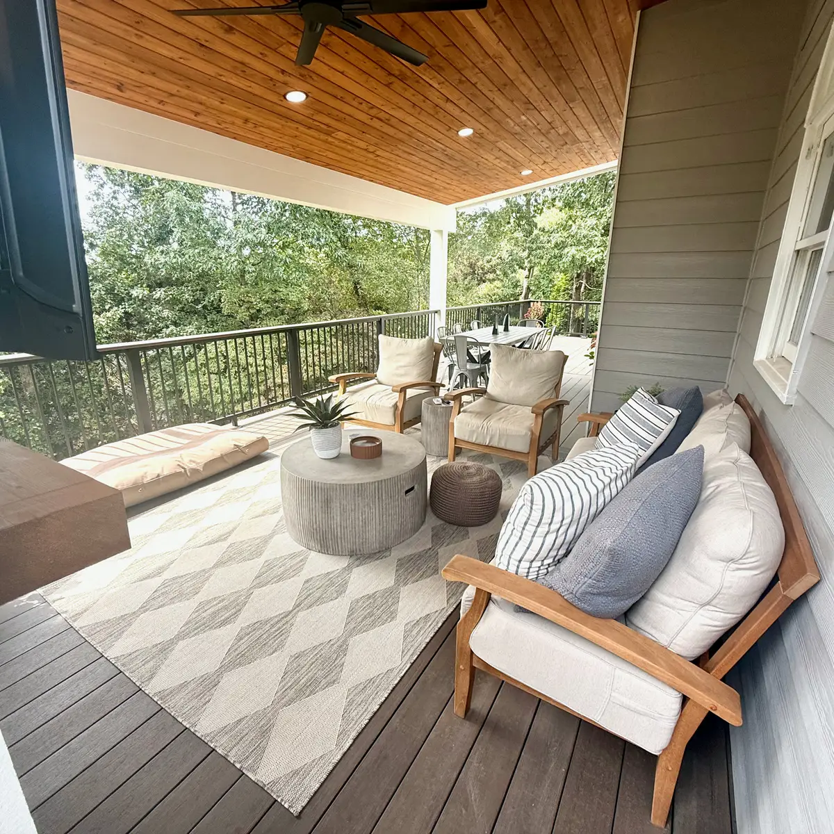 Covered deck seating area with outdoor rug and black railings