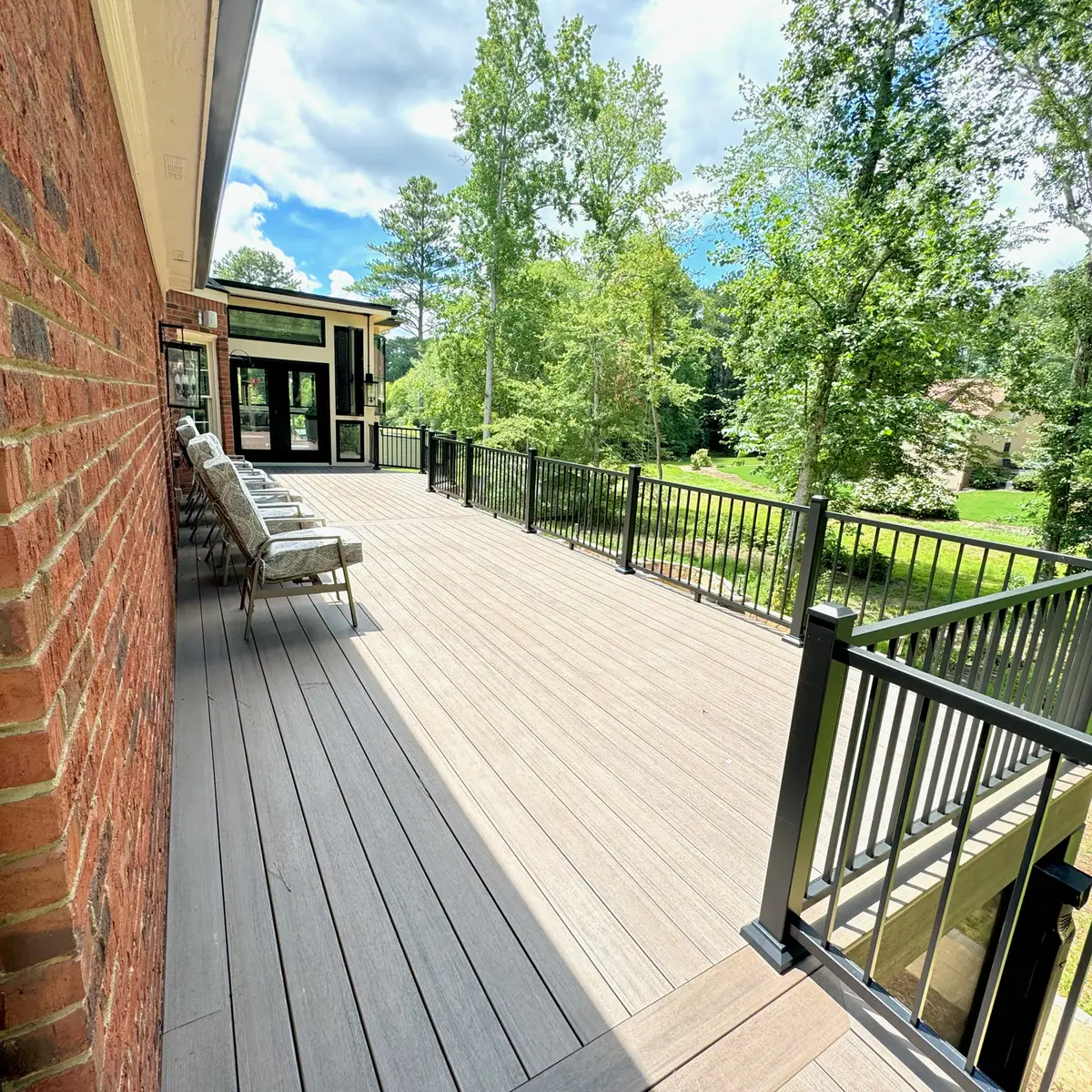 Long composite deck with black railings on a brick home