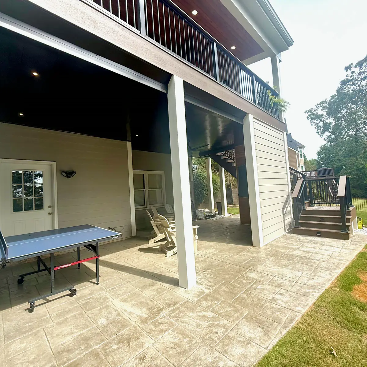 Covered patio under a deck with ping pong table and stairs