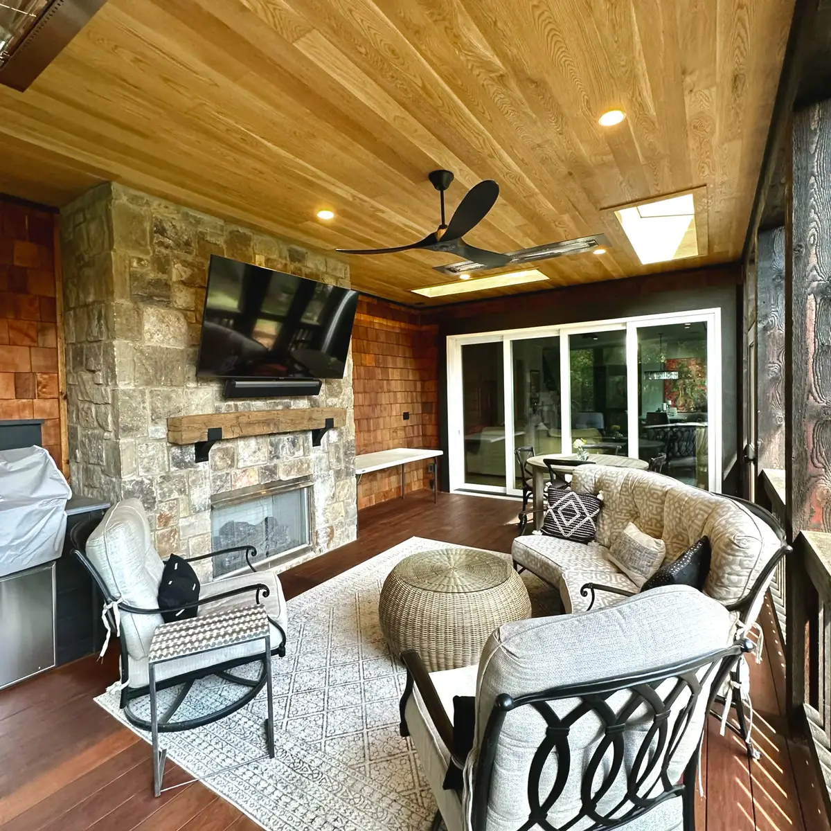 Screened porch with stone fireplace, cedar ceiling and mounted TV