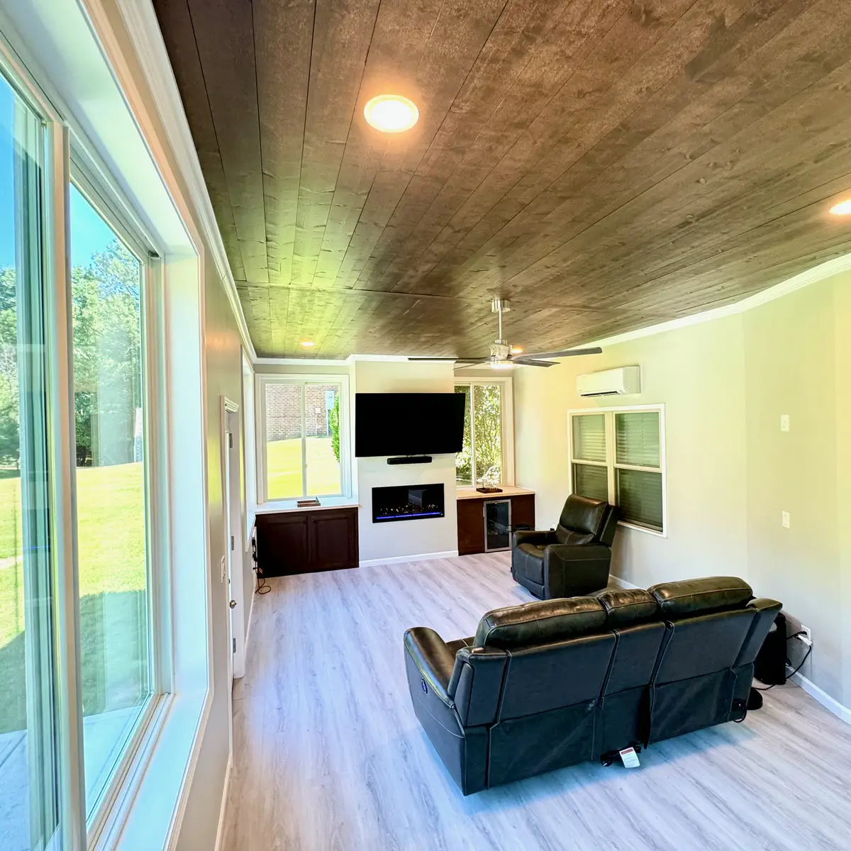 Sunroom with dark wood ceiling, electric fireplace and TV