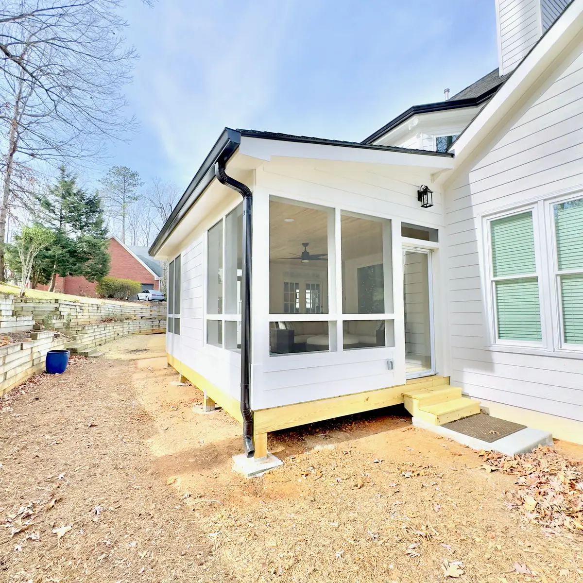 Sunroom addition with black gutters on a white home