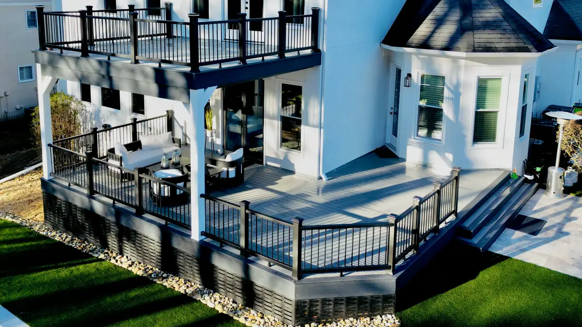 Aerial view of a two-story composite deck with black aluminum railings on a white home