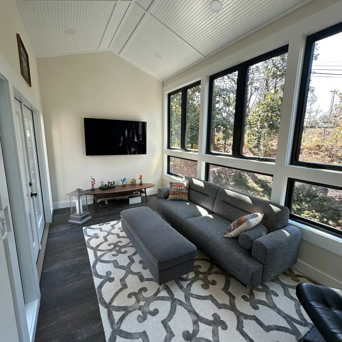 Sunroom with vaulted ceiling, black windows and TV